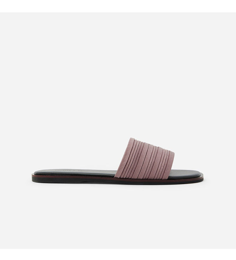 Women’s flat slide sandal with pleated mauve strap and black sole on white background