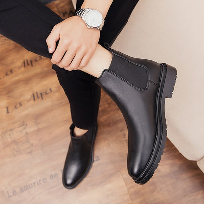 Men's black leather Chelsea boots with pointed toe and elastic side panels, worn with black pants
