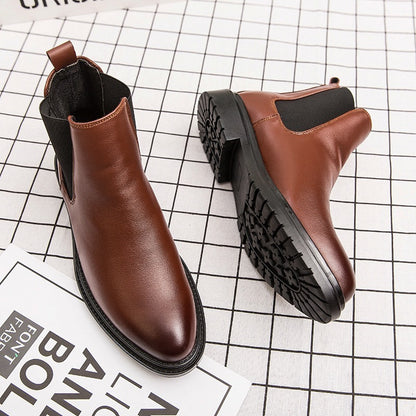 Pair of brown leather Chelsea boots with black elastic side panels on checkered background