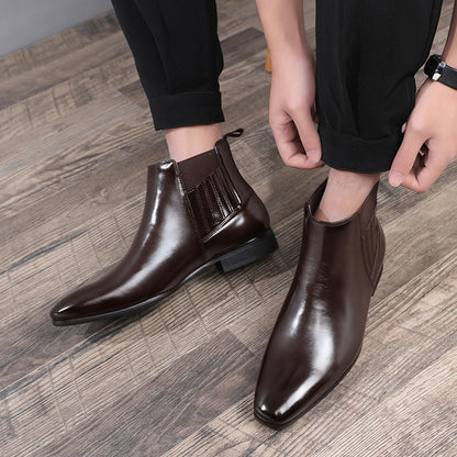 Men wearing polished brown leather Chelsea boots with pointed toes on wooden floor