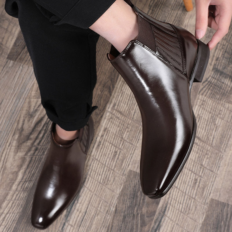 Men's dark brown leather Chelsea boots with pointed toe and elastic side panels on wooden floor