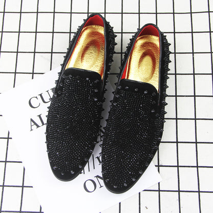 Men's black loafers with pointed toe, studded upper, and gold inner lining on grid background