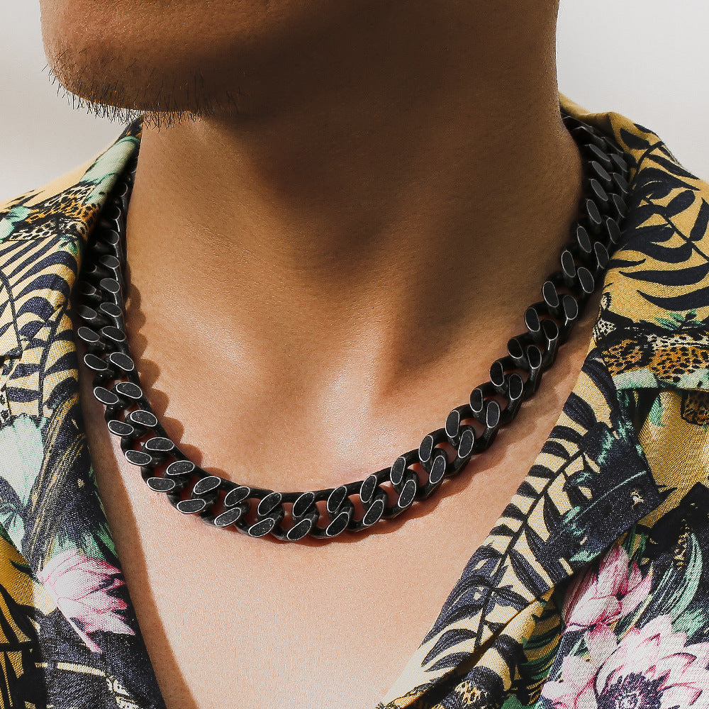Close-up of a man wearing a black titanium steel Cuban link chain necklace and a floral patterned shirt
