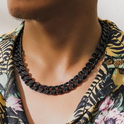 Close-up of a man wearing a black titanium steel Cuban link chain necklace and a floral patterned shirt
