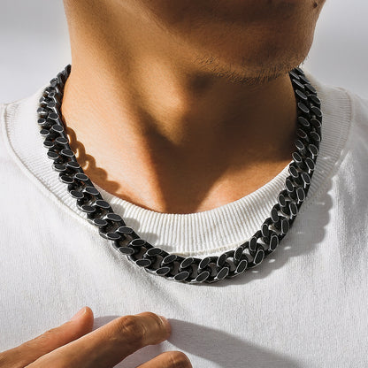 Close-up of a man wearing a durable 46cm black titanium steel Cuban link chain necklace with geometric design on white shirt