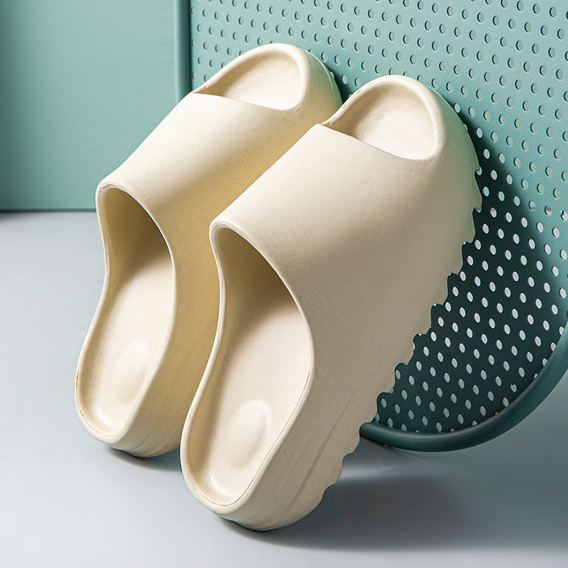 Cream-colored cushioned EVA slides with thick, wavy soles on a perforated green chair