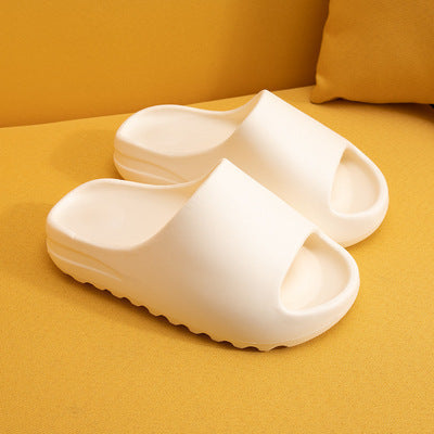 White cushioned EVA slippers with contoured footbed and textured sole on yellow surface