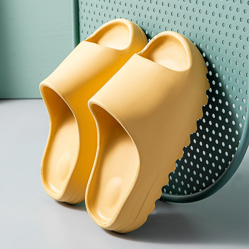 Pair of yellow cushioned EVA slippers with thick wave soles on a perforated teal chair
