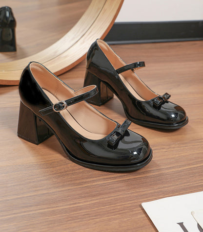Shiny black patent leather Mary Jane shoes with chunky heels and buckle straps on wooden floor