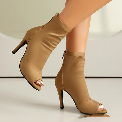 Tan women’s high-heeled ankle boots with peep toes and back zipper on smooth floor