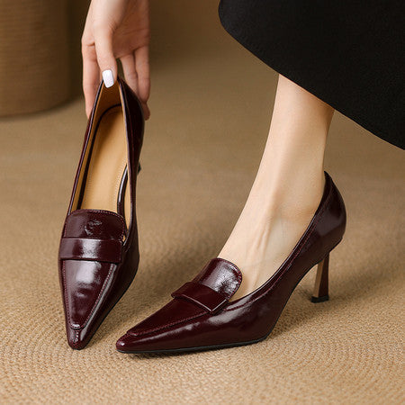 Women's burgundy patent leather pointed-toe pumps with mid heels on beige rug