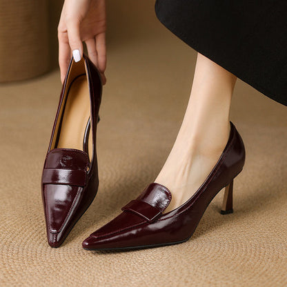 Women's burgundy patent leather pointed-toe pumps with mid heels on beige rug