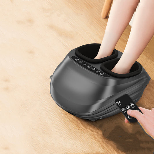 Black 4D heated foot massager with kneading therapy in use on wooden floor, remote control in hand