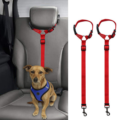 Red adjustable dog safety restraint attached to car headrest with small brown dog in blue harness seated on car seat