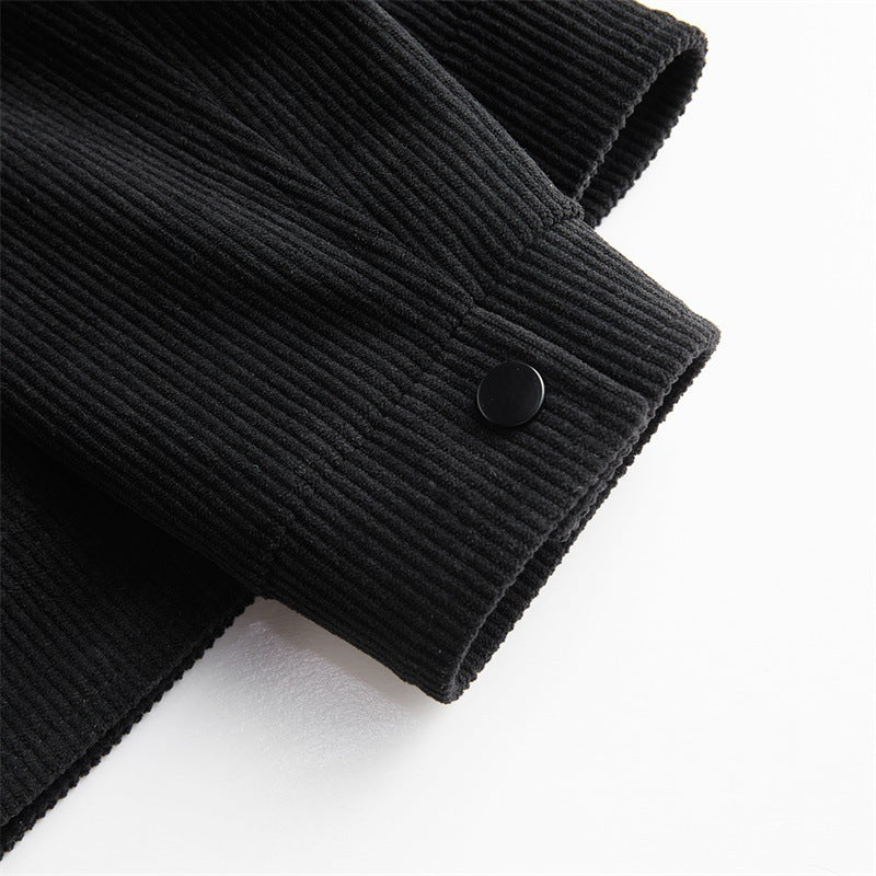 Close-up of black corduroy jacket sleeve with buttoned cuff on white background