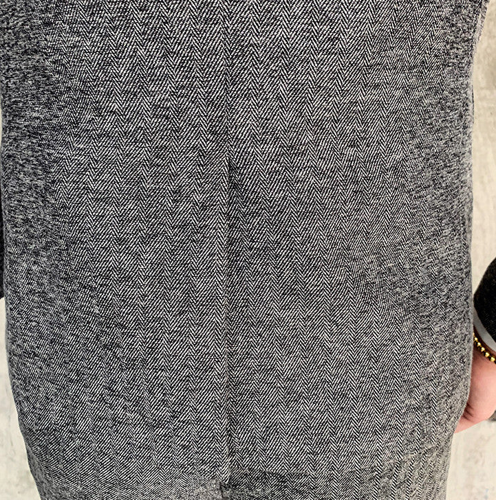 Close-up of men's black slim fit suit jacket with herringbone pattern and single button closure