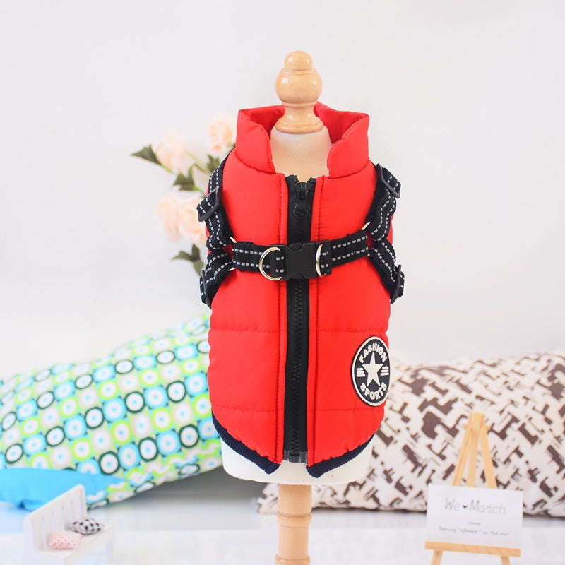 Red insulated dog coat with black harness on mannequin, decorative pillows in background