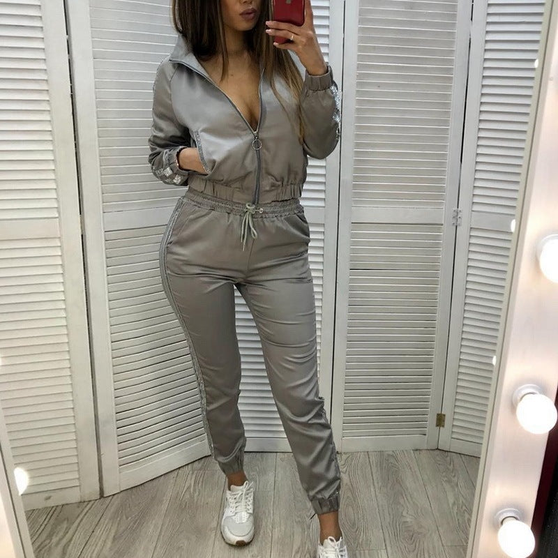 Woman in silver-gray polyester zip-up jacket and matching jogger pants with striped cuffs and white sneakers in dressing room