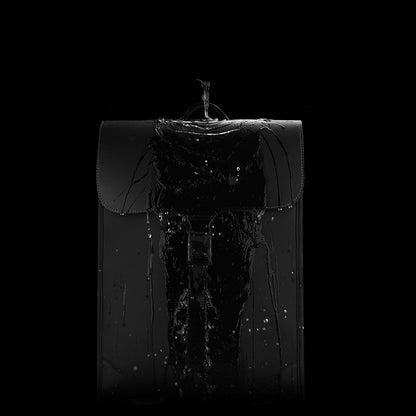 Black waterproof PU leather shoulder bag with water pouring over it, highlighting its water-resistant feature