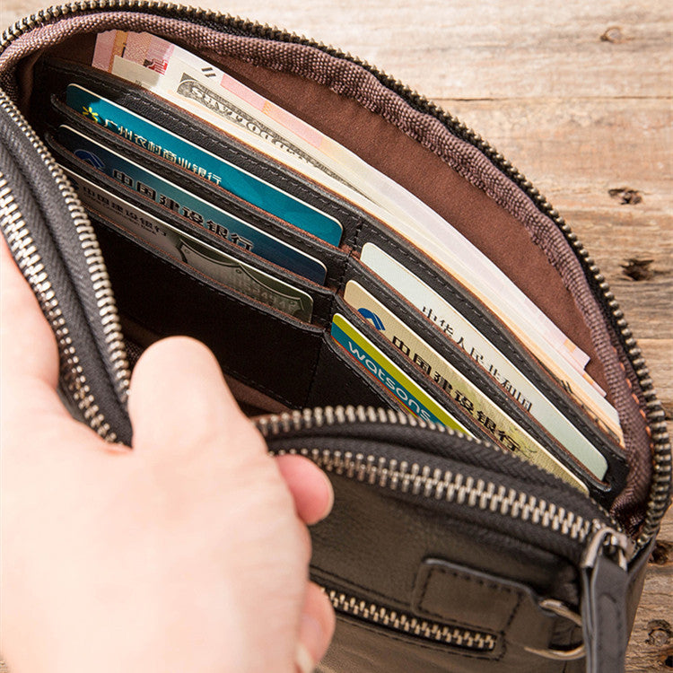 Hand holding open black leather men's clutch bag with multiple card slots and cash inside