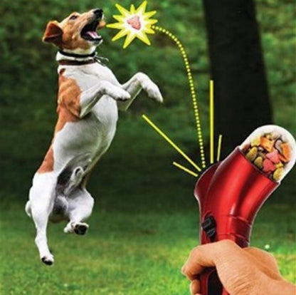Interactive red pet treat launcher with ergonomic grip shooting treats for brown and white dog in grassy outdoor park