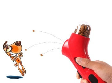 Hand holding red pet treat launcher toy shooting treats toward cartoon dog