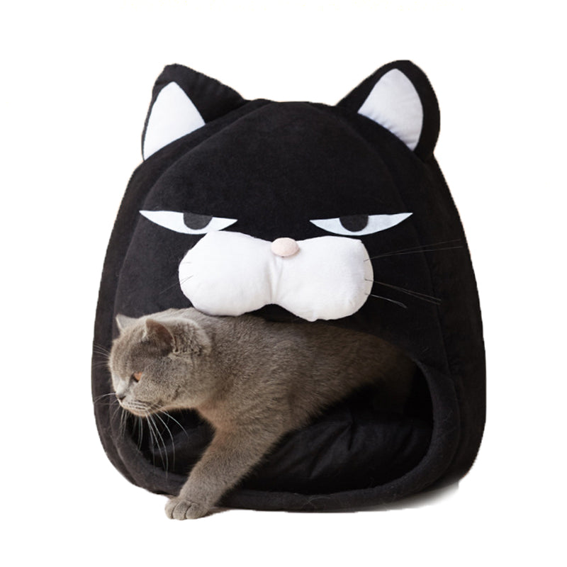 Gray cat exiting black cozy cat bed shaped like a cat face with white details and plush texture