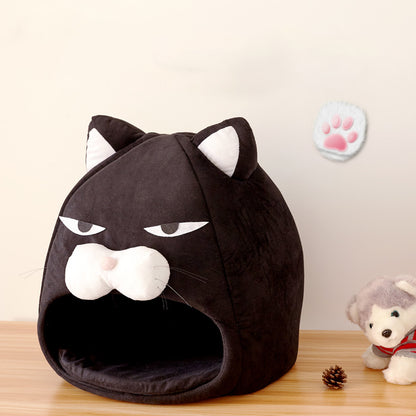 Black cat-shaped plush pet bed with white ears and snout on wooden surface