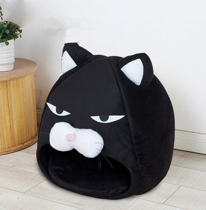 Black cat-shaped plush pet bed with white ears and snout, placed on light wood floor