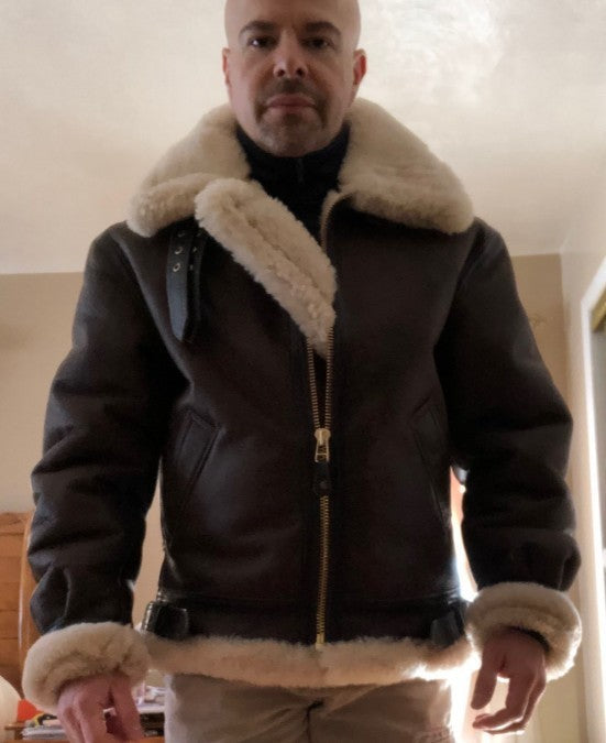 Man wearing a black faux leather winter jacket with thick beige shearling collar and cuffs