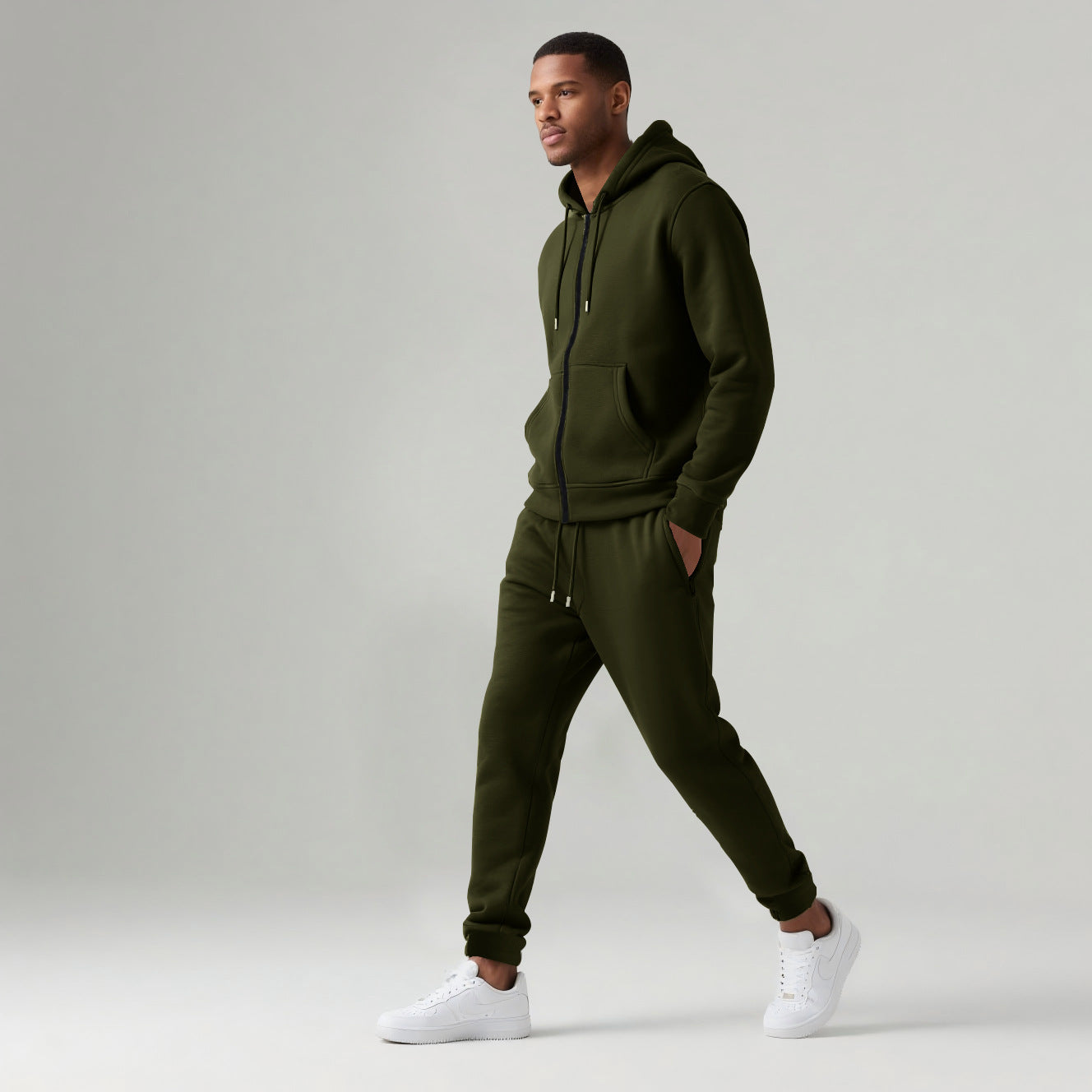 Man wearing olive green cotton blend hooded zip-up tracksuit with joggers and white sneakers