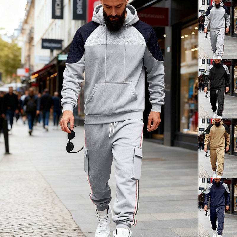 Man wearing black and gray color-block hoodie and gray cargo sweatpants walking in urban street casual wear