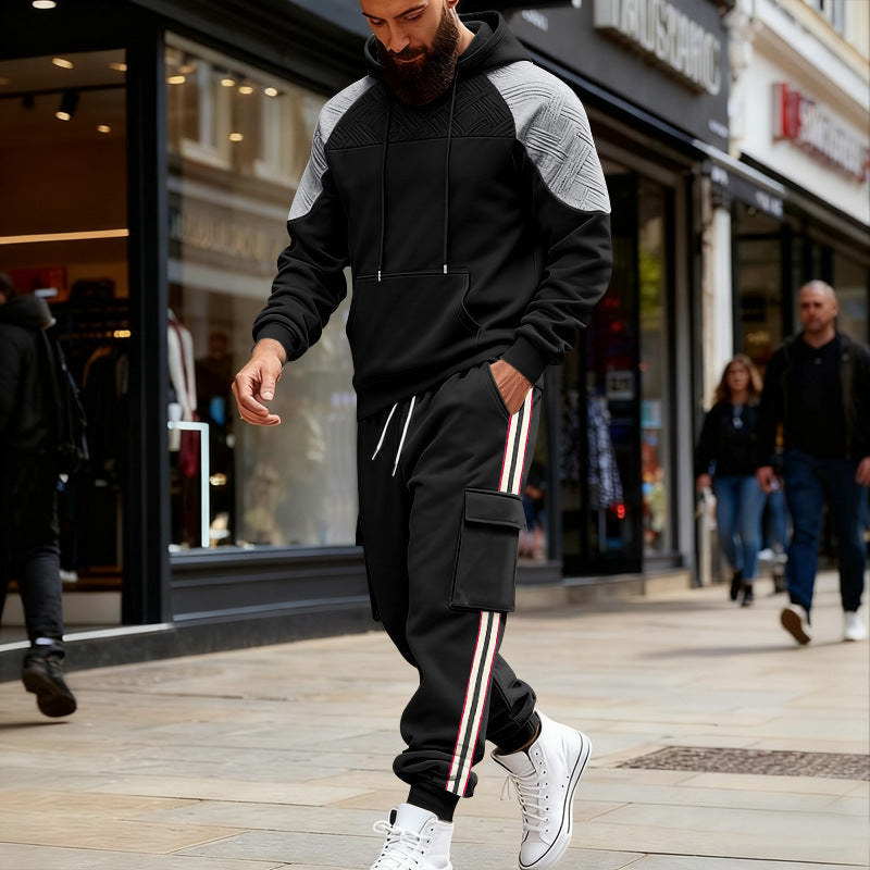 Man walking on city street wearing black and gray color block hoodie and black cargo sweatpants with side stripes
