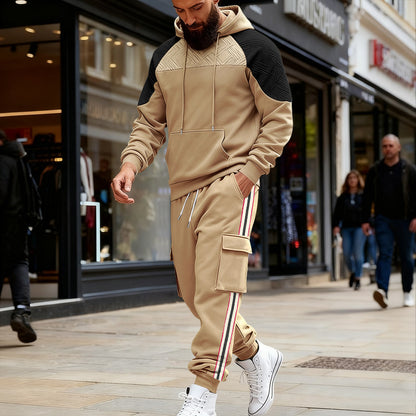 Man wearing beige and black color-block hoodie with matching cargo sweatpants and white high-top sneakers on city street