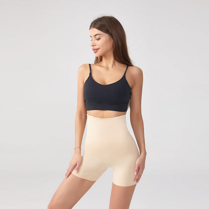 Woman wearing beige high-waist shaping shorts with tummy control and black crop top on plain background