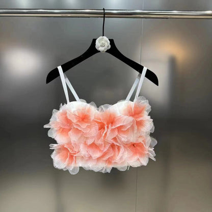 White crop top with orange halo-dyed floral ruffles on black hanger against gray background