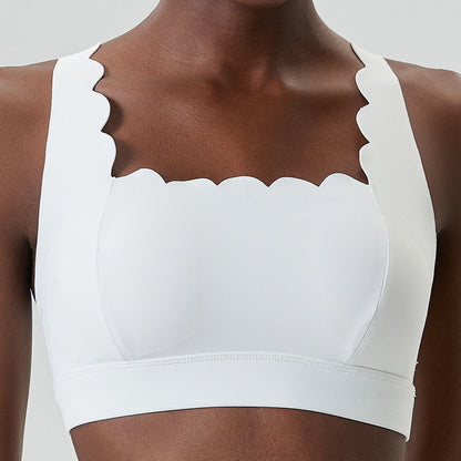 Close-up of a woman wearing a white sports bra with scalloped edges and wide straps