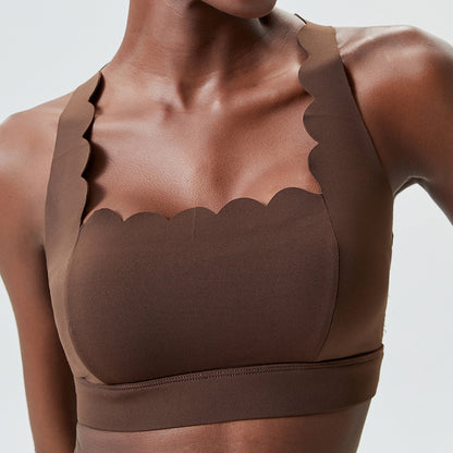 close-up of a woman wearing a brown scalloped-edge sports bra with wide straps on a white background