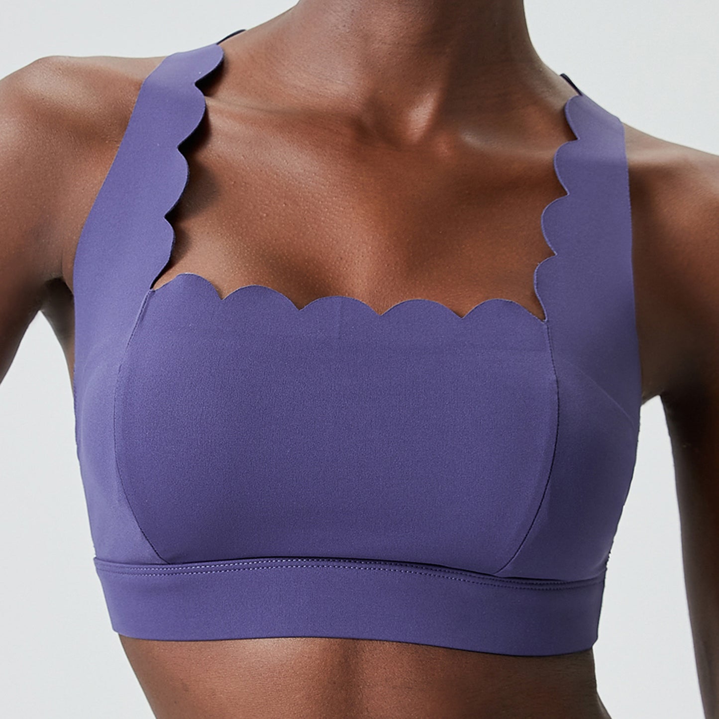 Close-up of woman wearing purple scalloped-edge sports bra, showing smooth fabric and fit