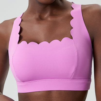Close-up of woman wearing pink sports bra with scalloped edge design on neckline and straps