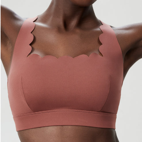 Close-up of woman wearing a pink sports bra with scalloped edges and thick straps