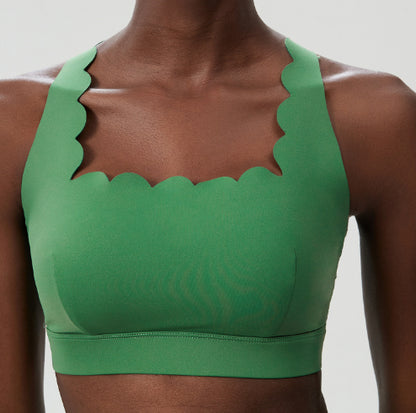 Close-up of a woman wearing a green scalloped edge sports bra on a plain background