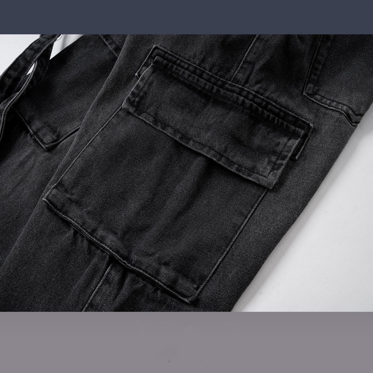 Close-up of black washed distressed denim jeans with large flap pockets