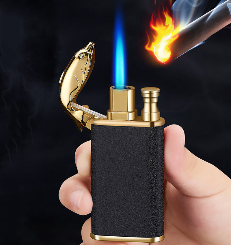 Hand holding black and gold metal double flame lighter with fish-shaped cap lighting a cigar