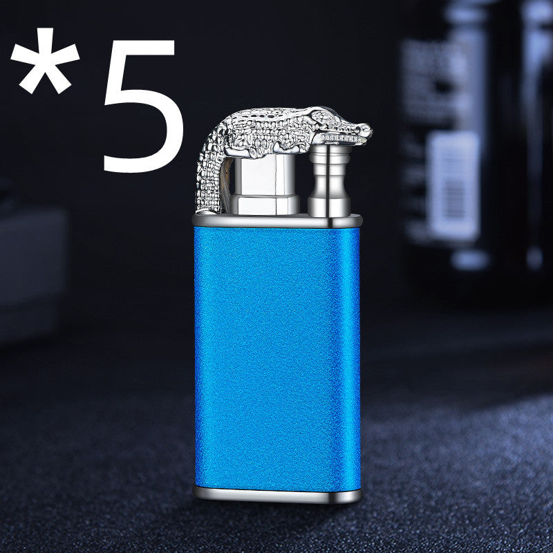 Blue metal windproof double-flame lighter with silver crocodile design on top in dark setting