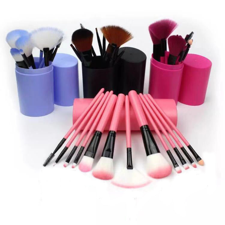 Set of 12 pink makeup brushes with black ferrules and soft bristles, displayed with purple, black, and pink brush holders
