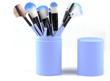 Blue makeup brush set with soft bristles in a matching cylindrical container with lid on white background