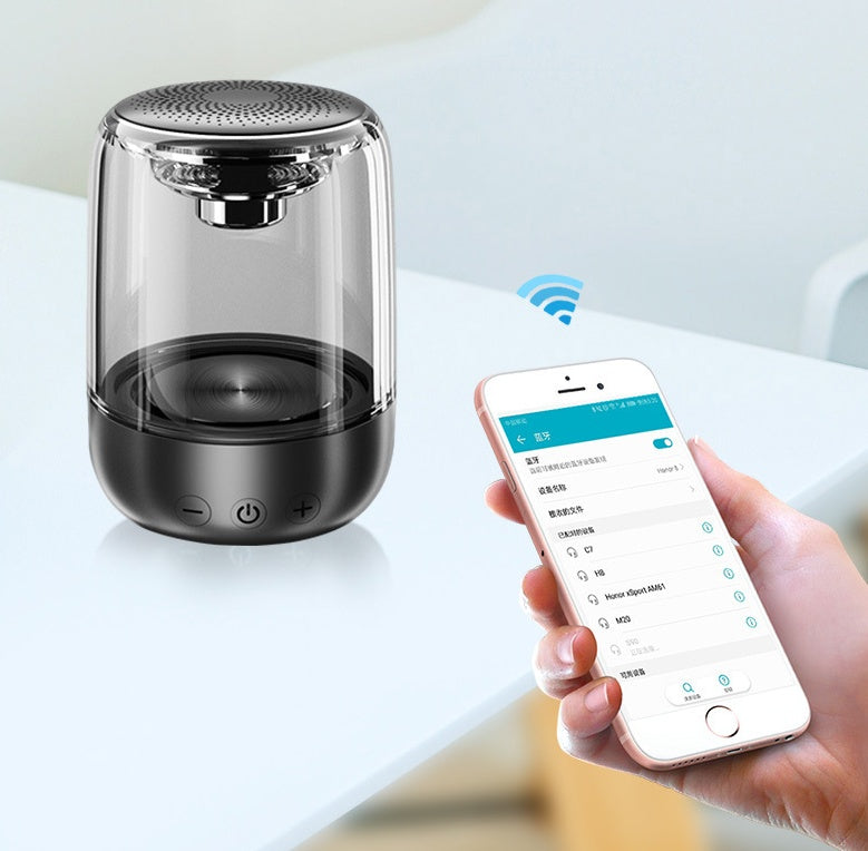 Portable Bluetooth speaker with transparent casing next to smartphone showing wireless pairing