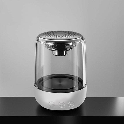 Transparent portable Bluetooth speaker with white base and touch controls on black table