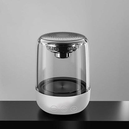 Transparent portable Bluetooth speaker with white base and touch controls on black table
